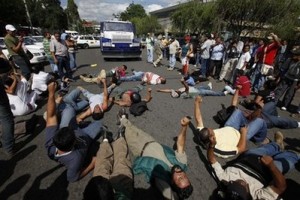 Seguidores del presidente Manuel Zelaya gritan consignas acostados en el suelo en Tegucigalpa. (Foto AP)