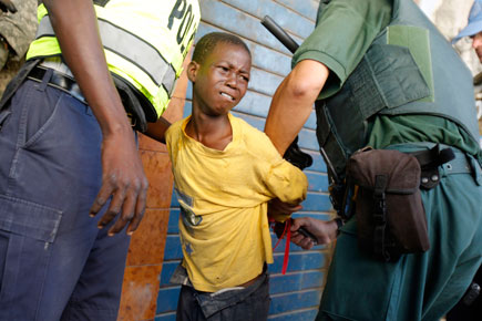En la imagen, policías detienen a un niño acusado de saqueo. Foto Reuters