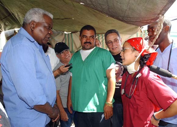 Esteban Lazo (I), miembro del Buró Político del Partido Comunista de Cuba, intercambia con una de las doctoras norteamericanas graduadas en la ELAM en el hospital de campaña de Croix des Bouquets, Haití, durante una visita de trabajo a Haití el 8 de febrero de 2010. AIN Foto: Juvenal Balan Neyra