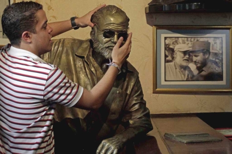 Un turista pone sus gafas sobre una estatua de Hemingway en La Habana. Foto: AP