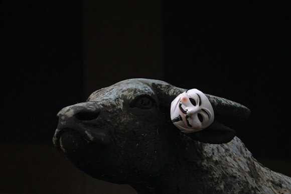 Una máscara de Guy Fawkes hizo popular por 'V de Vendetta' en la novela gráfica cuelga del cuerno de buey de bronce de una escultura fuera de la Bolsa de Hong Kong