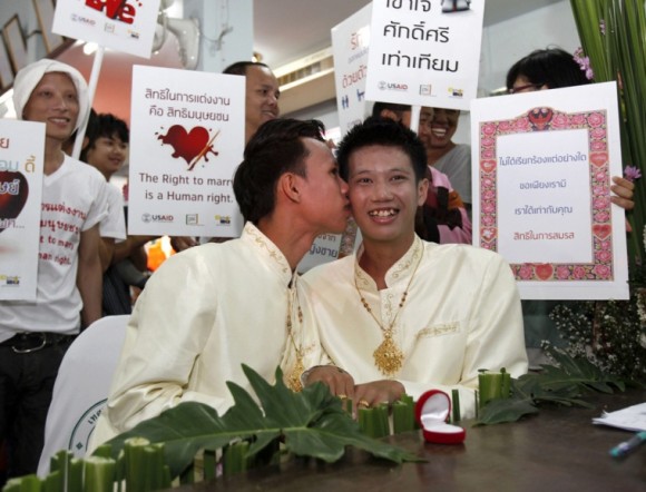 El tailandés Jedwarut Boonpan, besa a su pareja, Nattapol Panumong, mientras sus amigos sujetan pancartas pidiendo el derecho a las parejas homosexuales a casarse, durante su boda celebrada el día de San Valentín, en la provincia de Chiang Mai, al norte de Tailandia. Foto: Pongmanat Tasiri / EFE