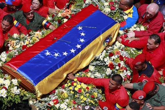 Varias personas sostienen el féretro que contiene el cuerpo de Hugo Chávez en el traslado del hospital donde falleció a la academia militar donde reposaría hasta su funeral en Caracas el 6 de marzo. Foto: Ricardo Mazalan/AP.