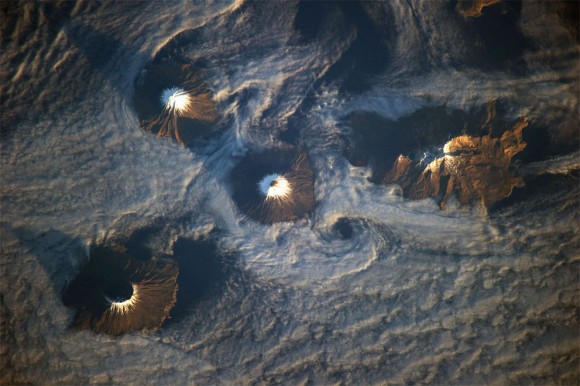  islas de las cuatro montañas se ofrecen en esta imagen fotografiada por un miembro de la tripulación Expedición 38 de la ISS el 15 de noviembre de 2013. Mañana luz del sol ilumina las pistas de orientación al sureste de las islas de la fotografía. Las islas, parte de la cadena de las islas Aleutianas , en realidad son las laderas superiores de los volcanes se elevan desde el fondo del mar ; Carlisle , Cleveland, Herbert , y Tana . (NASA )