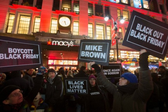 Manifestantes indignados por el fallo de no fincar cargos contra el agente de Ferguson que mató a un joven afroestadunidense, se apostaron frente a una tienda departamental en Nueva York, horas antes de que arrancara el Viernes Negro. Foto Reuters