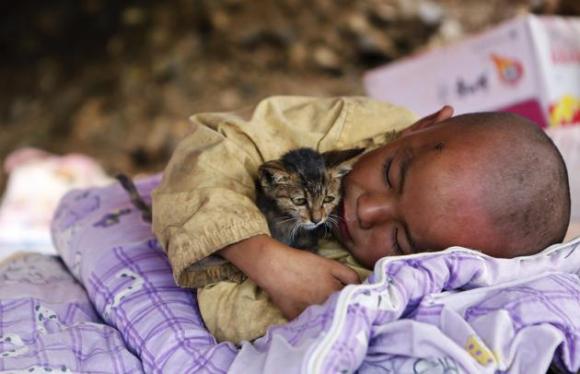 Un niño abraza un gato, mientras descansa en un refugio en la zona donde ocurrió el terremoto en el condado de Ludian, en la provincia de Yunnan este 5 de agosto de 2014. Un terremoto ocurrido en China durante el f