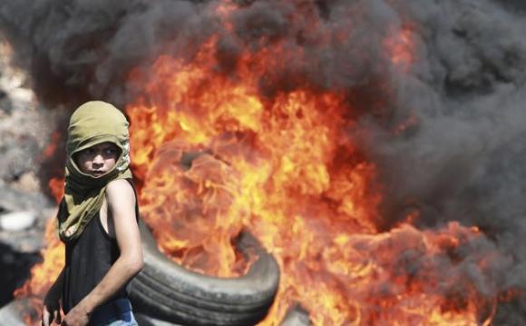 Un niño palestino mira de cerca la quema de neumáticos durante los enfrentamientos con soldados israelíes a raíz de una protesta cerca del asentamiento judío de Qadomem este 19 de septiembre 2014 .REUTERSAbed Omar