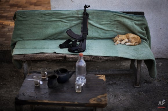 Un gato duerme junto a un arma Kalashnikov en un puesto de control de seguridad de Hamas en Ciudad de Gaza, 30 de octubre de 2012. (Foto AP / Bernat Armangue)