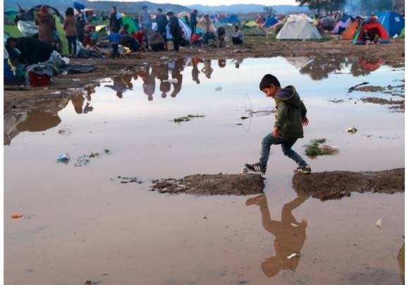 Niño refugiado juega en medio del fango. Foto: AP.