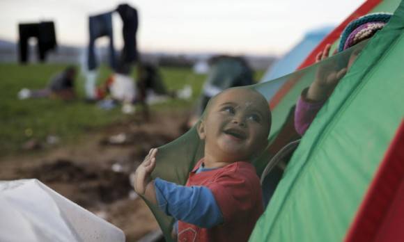 Niño refugiado sonríe en casa de campaña. Foto: Reuters.