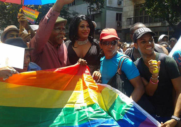 Wilber Pérez (Chacón, izq.) y Omar Franco (Ruperto, der.) sostienen una bandera con los colores identitarios de la comunidad LGTBI. Foto tomada del perfil de Facebook de Yunel Labacena.